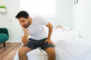 homem-bonito-irritado-de-pijama-sentado-na-cama-e-pensando-na-briga-com-raiva-com-sua-namorada-adormecida_662251-415