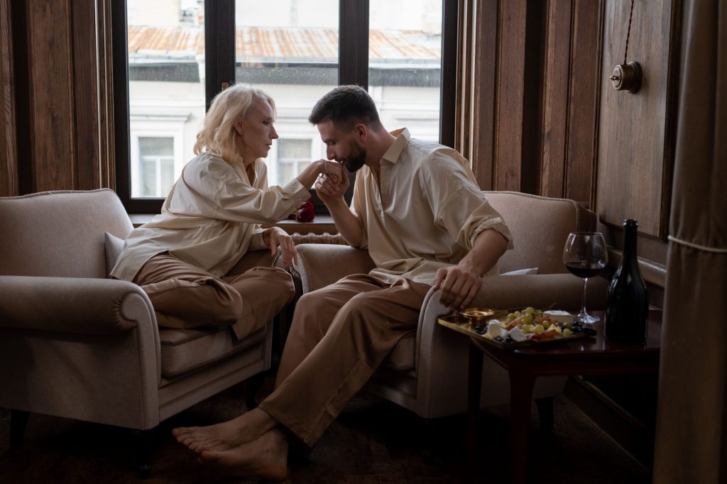 A couple sharing a romantic moment in a cozy living room with wine and snacks.