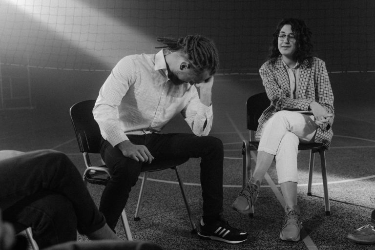 A therapy session with people discussing mental health in a supportive environment.