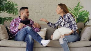 A couple having an argument while sitting on a sofa indoors, showcasing conflict in a relationship.
