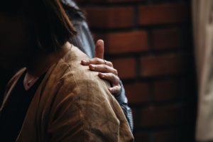 A close-up of a comforting hand on a woman's shoulder, symbolizing emotional support.