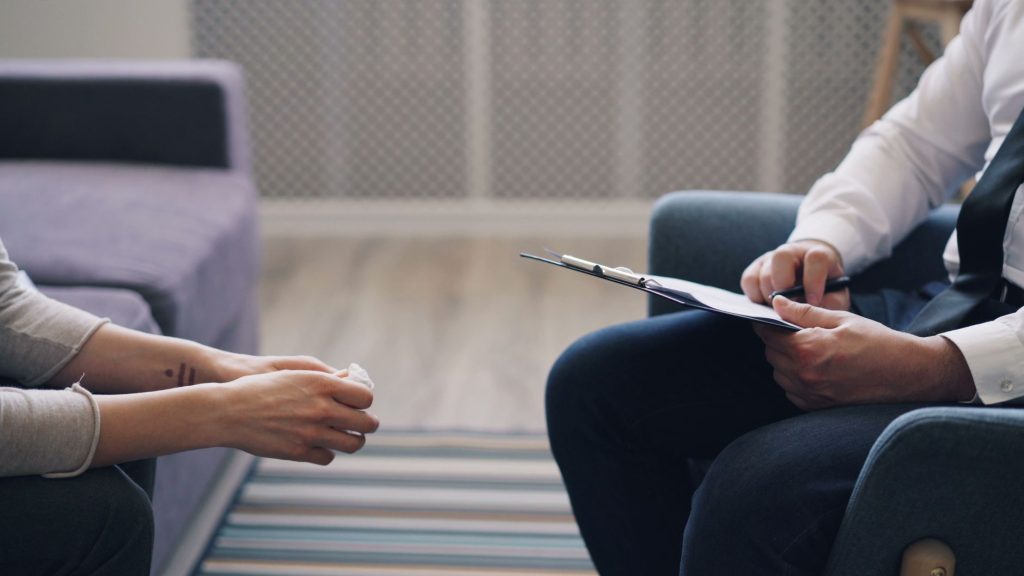 f6b64e83 6dc5 4f9a b938 09d4363f6290 A therapy session with a psychologist and patient, discussing mental health indoors.