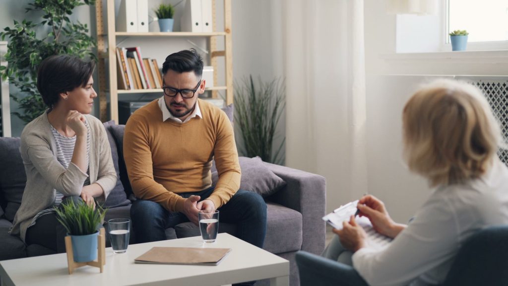 5c030071 ffe0 4920 8151 570412e85fa4 A couple engaged in a counseling session with a therapist in a cozy room.