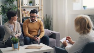 A couple engaged in a counseling session with a therapist in a cozy room.