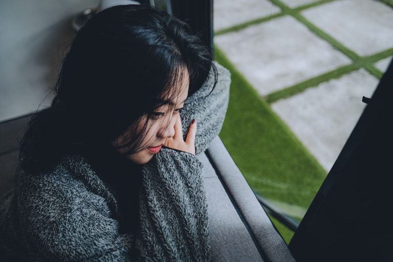 d6518a72 04d5 4f0c bd58 acb00e5efa8a A young Asian woman in a gray sweater gazes pensively out a window in Indonesia.