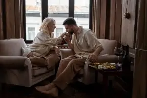 A couple sharing a romantic moment in a cozy living room with wine and snacks.
