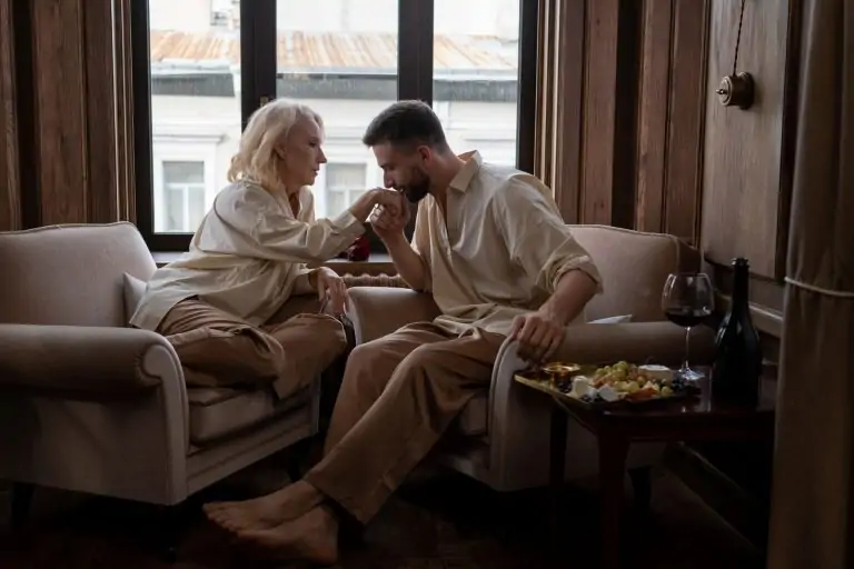 A couple sharing a romantic moment in a cozy living room with wine and snacks.