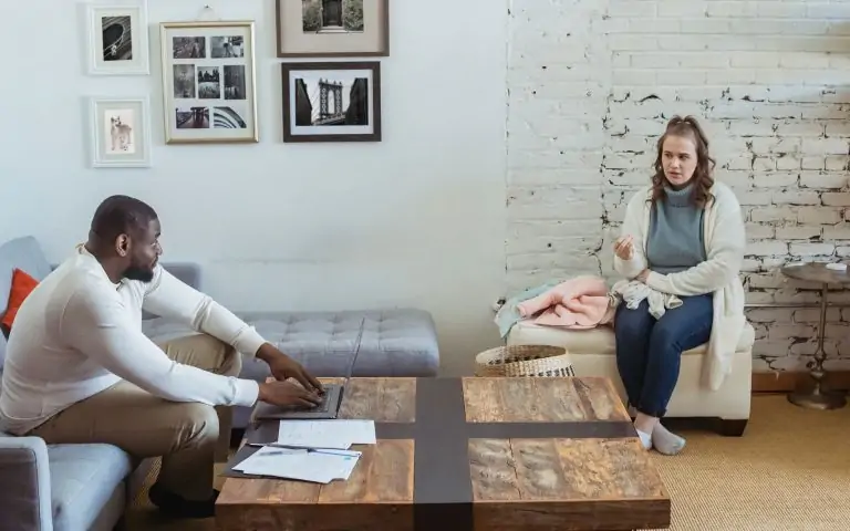 Full body of multiracial couple sitting in living room and sorting things out