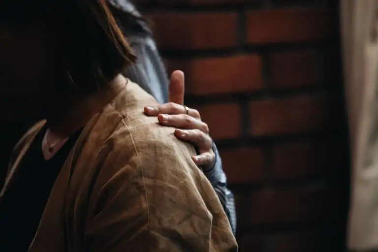 bc38aef8 f576 4965 9be7 9c8a9e90ba96 A close-up of a comforting hand on a woman's shoulder, symbolizing emotional support.